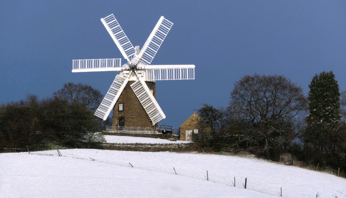 Heage Windmill viewed from across fields covered in snow
