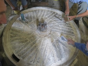 Cleaning the bed stone. Note the bearing at  the eye, or centre of the stone, and the hole ,left foreground , where the flour falls through  to be processed on the floor below